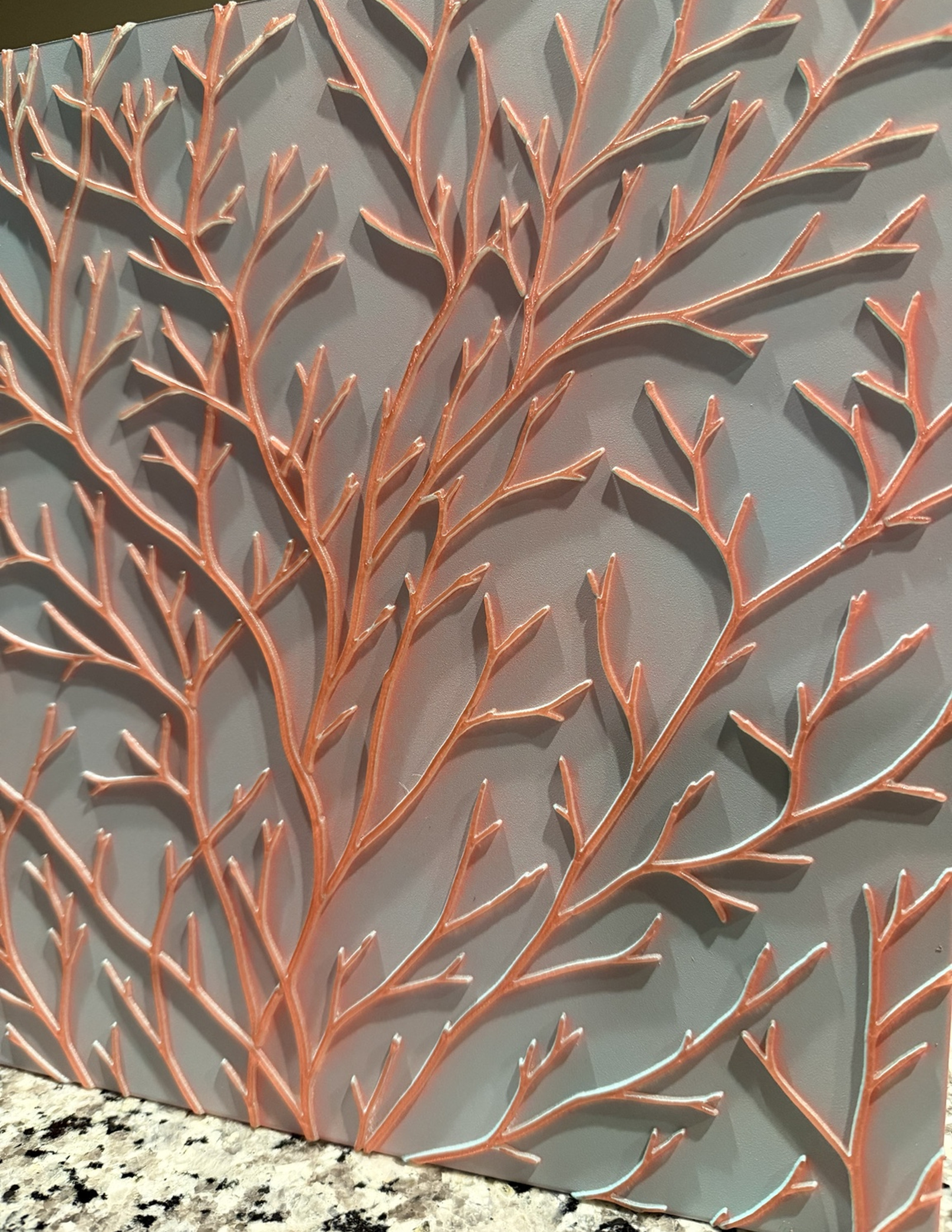 Botanical Relief panel with warm metallic branches, shown upright in angled light